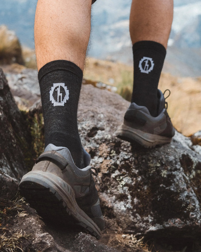 Black Trail Lightweight Alpaca Wool 3/4 Crew Hiking Socks on Man’s Legs with Hiking Boots on Rock – PAKA Apparel