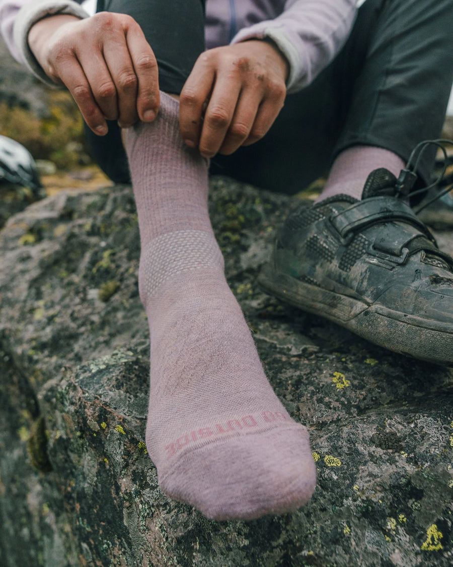 Person Putting on Quail / Pink Trail Alpaca 3/4 Crew Socks on Right Foot While Rock Climbing – PAKA Apparel