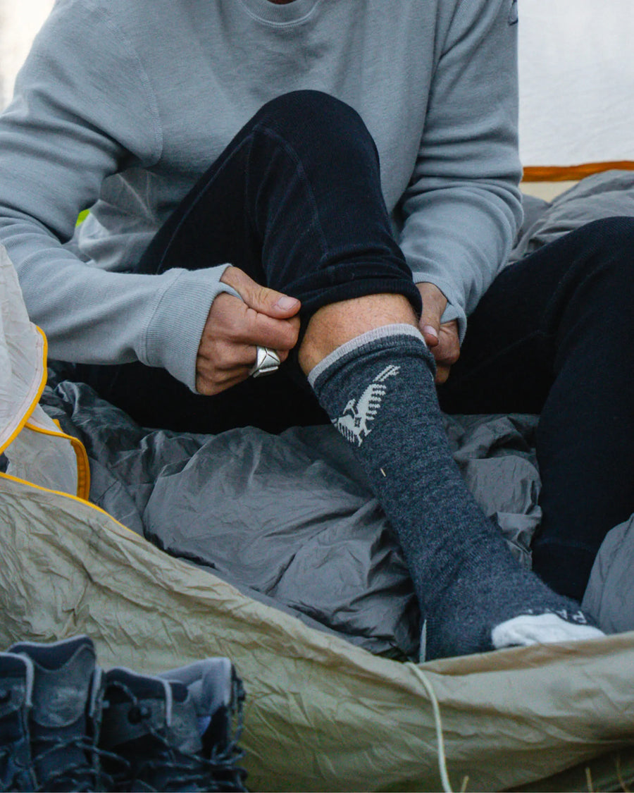 Lower Half of Man Putting on Charcoal / Dark Grey Condór Alpca Socks in Tent – PAKA Apparel