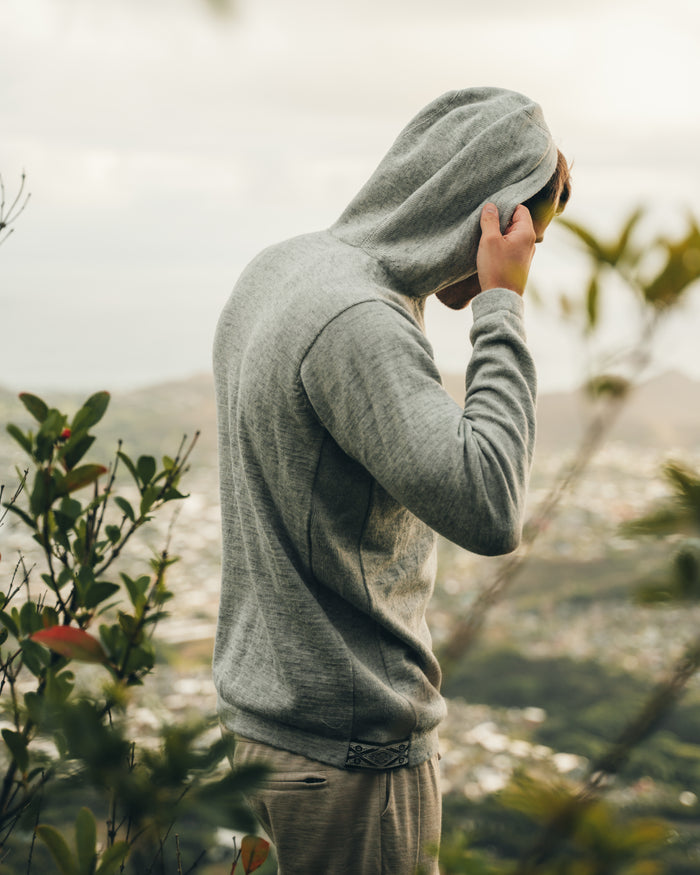 Man pulling up hood of grey alpaca hoodie sweater 