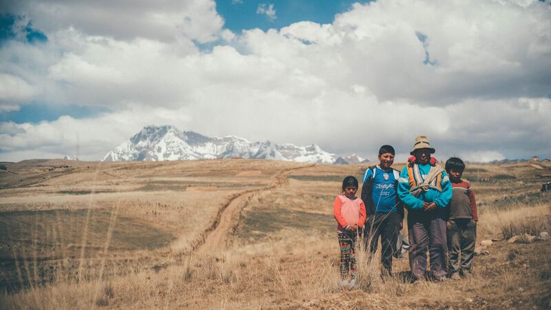 Peruvian Family with Father and Three Kids Standing in Field in Front of Mountain