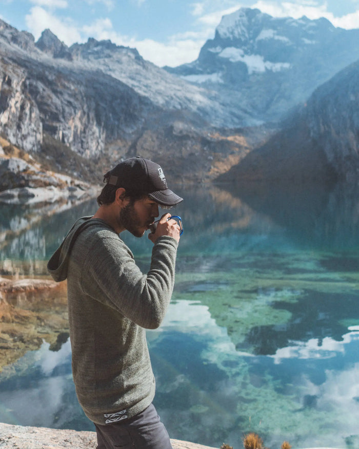 Man Sipping Coffee in The Hoodie Eucalyptus / Dark Green Alpaca Hiking Hoodie in Front of Mountains Reflected on Lake – PAKA Apparel