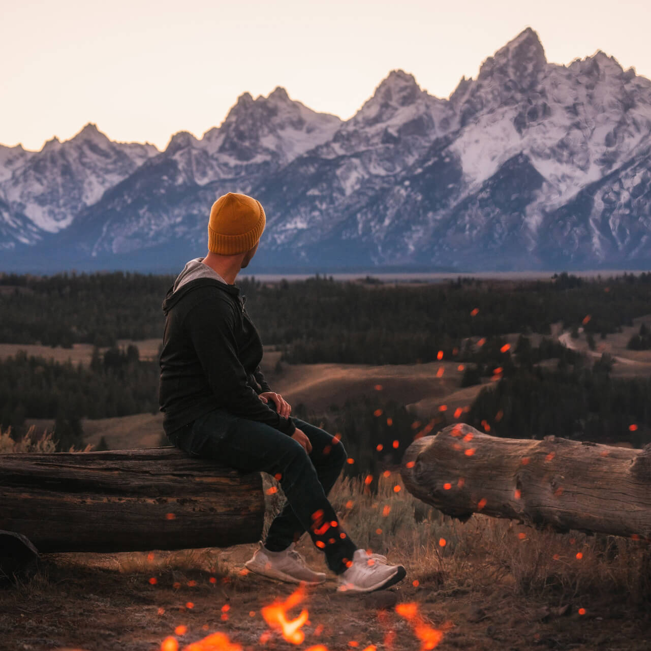 Man in Alpaca Performance Hoodie with Bonfire and Teton Mountain Range in Background - PAKA Apparel