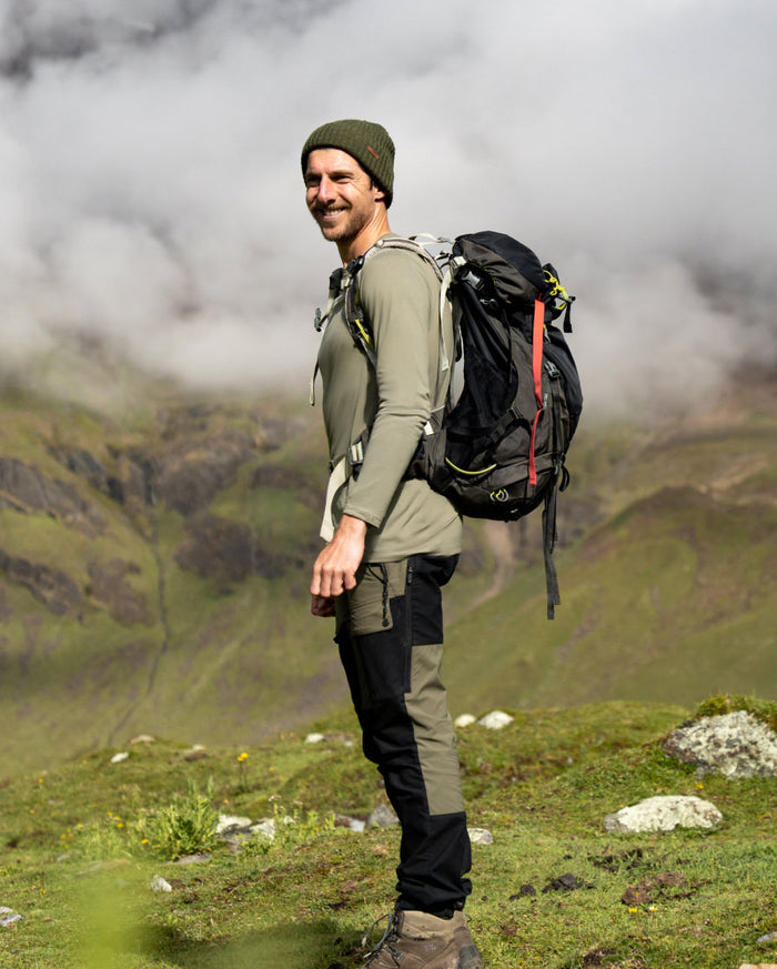 man wearing green alpaca base layer with backpack 