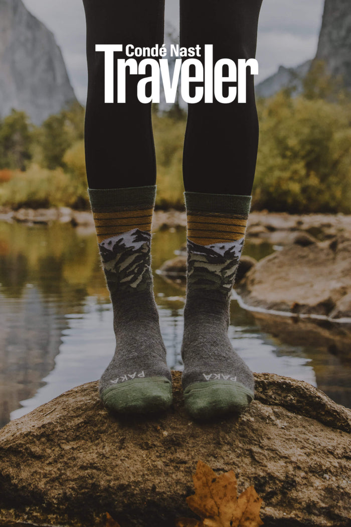 A lady wearing our amazing Mountain socks over a rock by a lake 