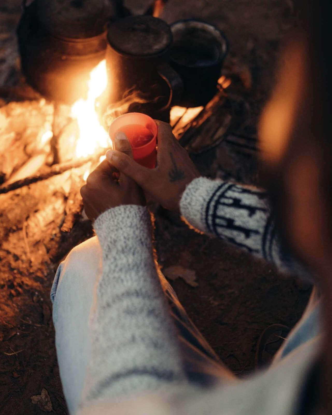 Person with Drink in Front of Bonfire Wearing The Costa Alpaca Wool Sweater - PAKA Apparel