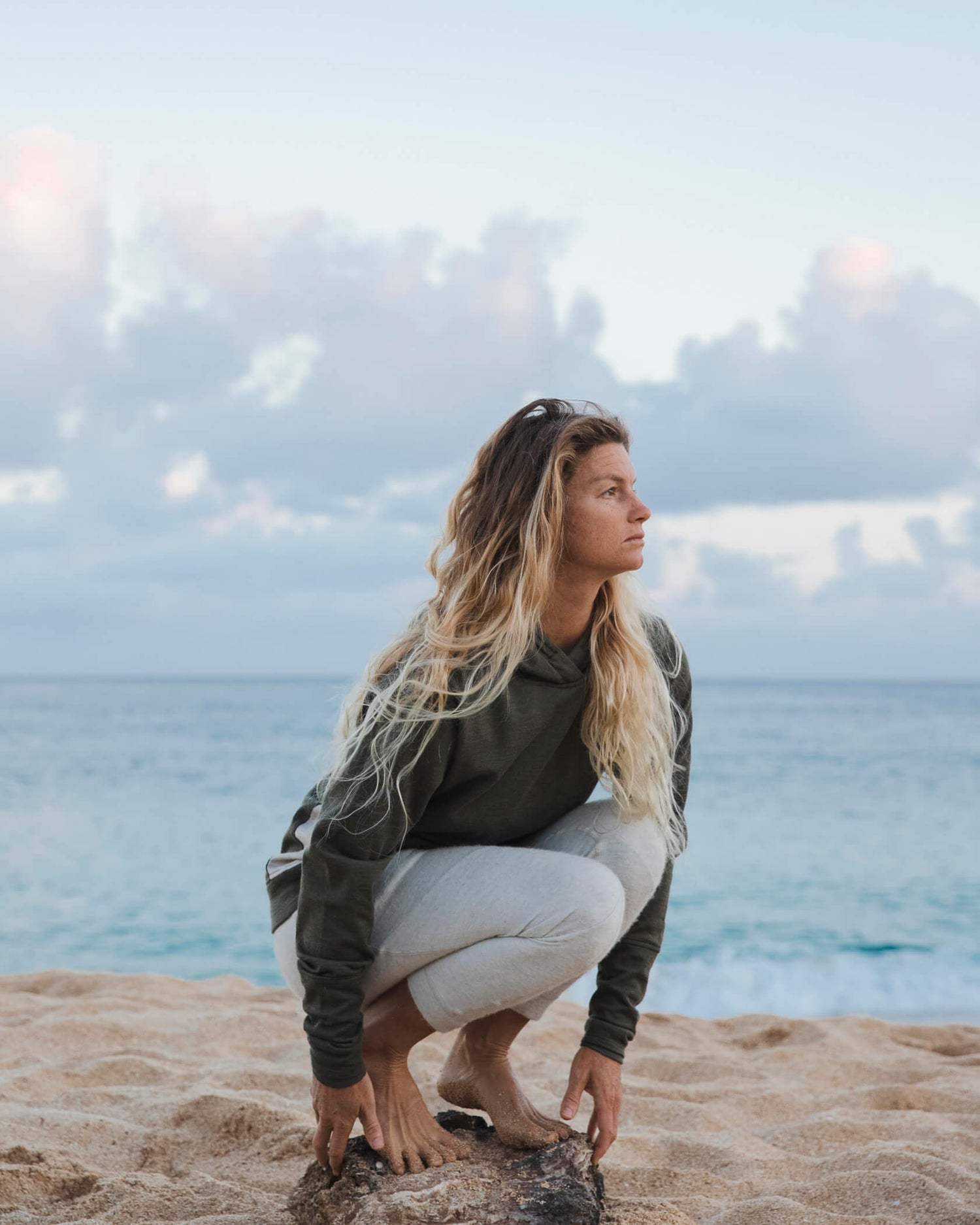 PAKA Ambassador Leah Dawson, Pro-Surfer, Crouching Down in Front of Ocean