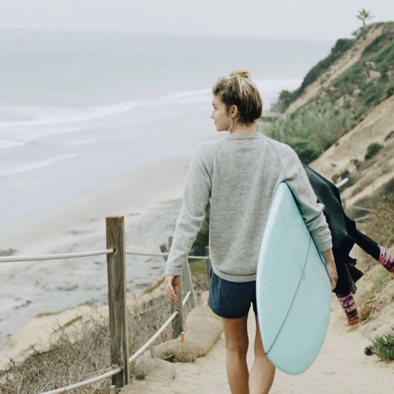 Woman Surfer with Board Walking Down to Ocean Wearing Alpaca Crewneck Sweater - PAKA Apparel