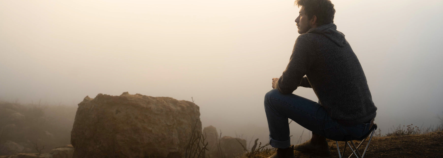 Man Sitting on Camp Chair in Mist Wearing The Vida Alpaca Wool Hoodie for Hiking and Outdoors – PAKA Apparel