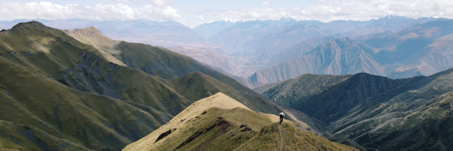 Mountain biker wearing alpaca clothing riding along the ridge of a mountain 