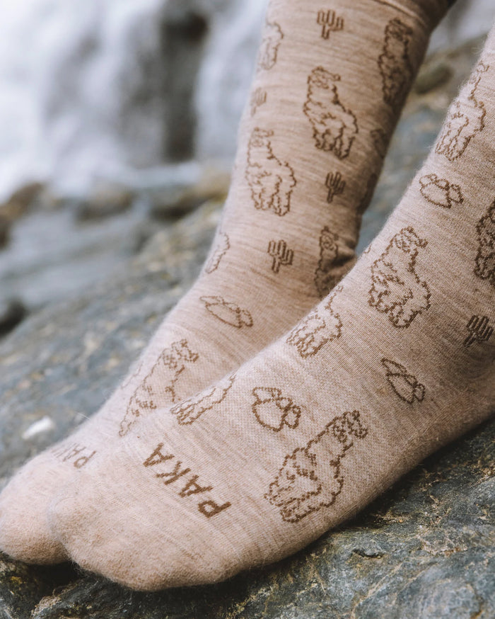 Timber / Tan Sebastian the Alpaca Pattern Graphic Peruvian Alpaca Crew Socks on Feet Resting on Rock – PAKA Apparel