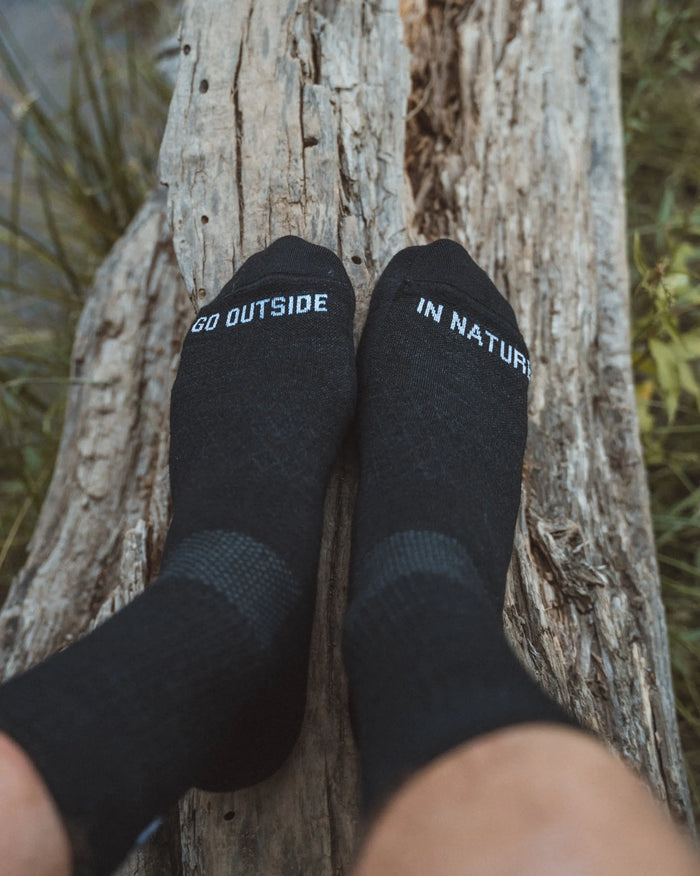 Above Shot of Legs Wearing Black Peruvian Alpaca Wool Crew Socks on Log – PAKA Apparel