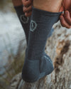 Charcoal Blue Alpaca Wool Crew Socks Being Pulled Up While Man's Legs Stand on Log – PAKA Apparel