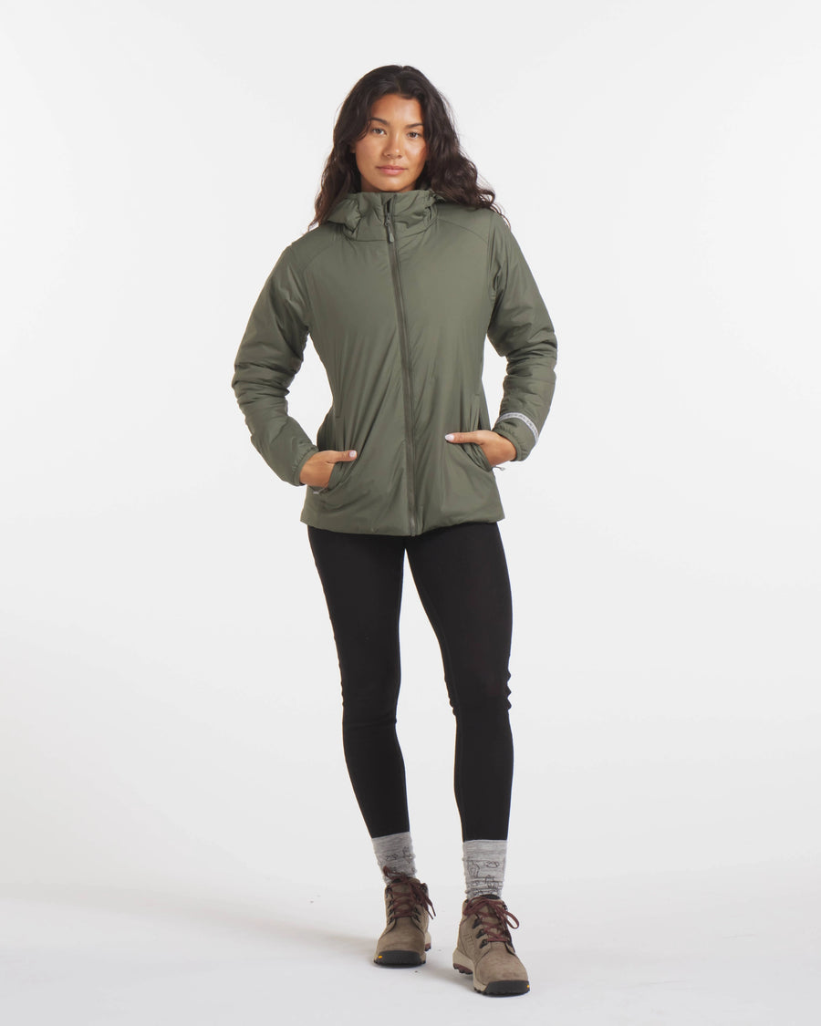 Woman with Hands in Pocket in Thyme / Dark Green Apu Lightweight Puffer Jacket for Travel – PAKA Apparel