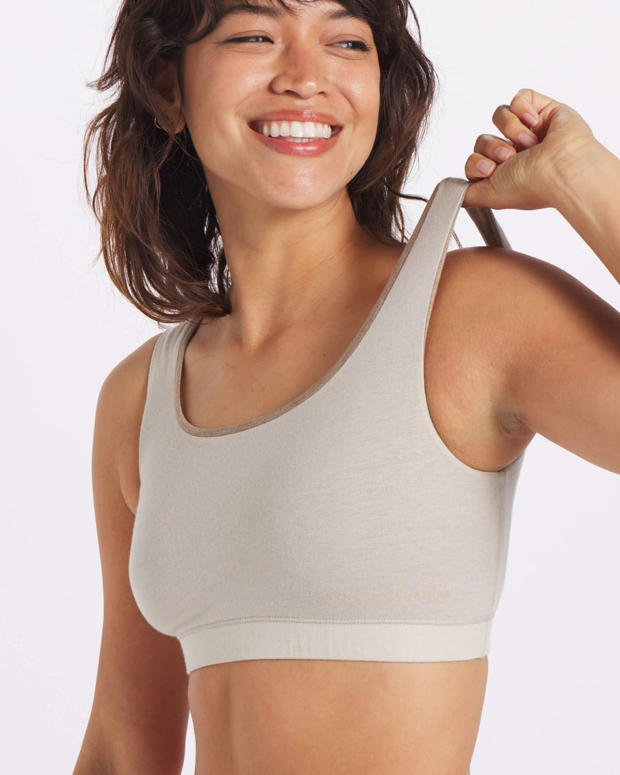 Woman Smiling and Stretching Shoulder Strap of Birch / Off-White Natural Fiber Bralette – PAKA Apparel