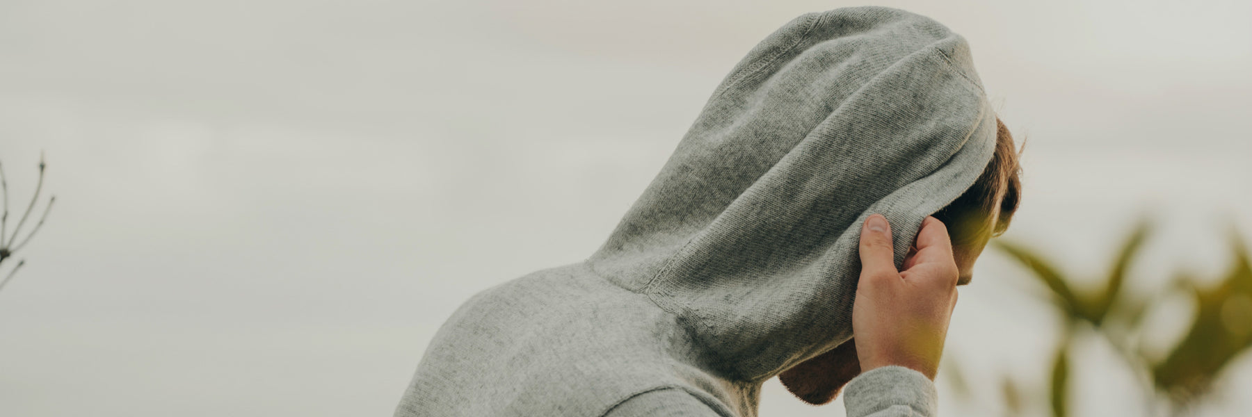 Man pulling up hood of grey alpaca hoodie sweater 