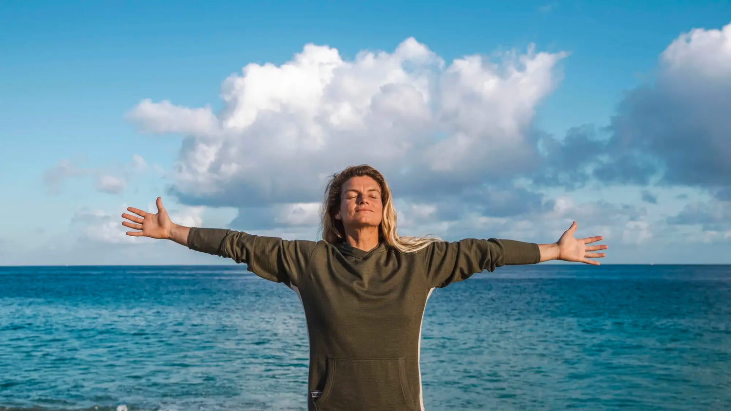 PAKA Ambassador Leah Dawson, Pro-Surfer, with Outstretched Arms in Front of Ocean