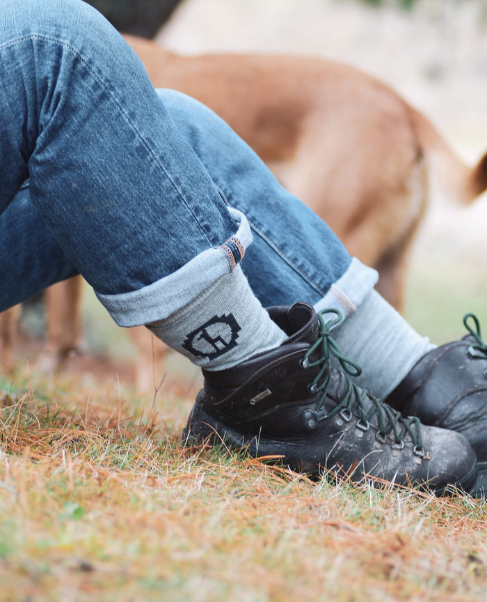 Photo of legs wearing jeans and light grey Paka socks outside on grass