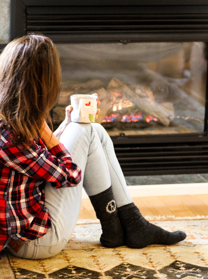 Woman Model wearing dark grey Paka socks in front of fire