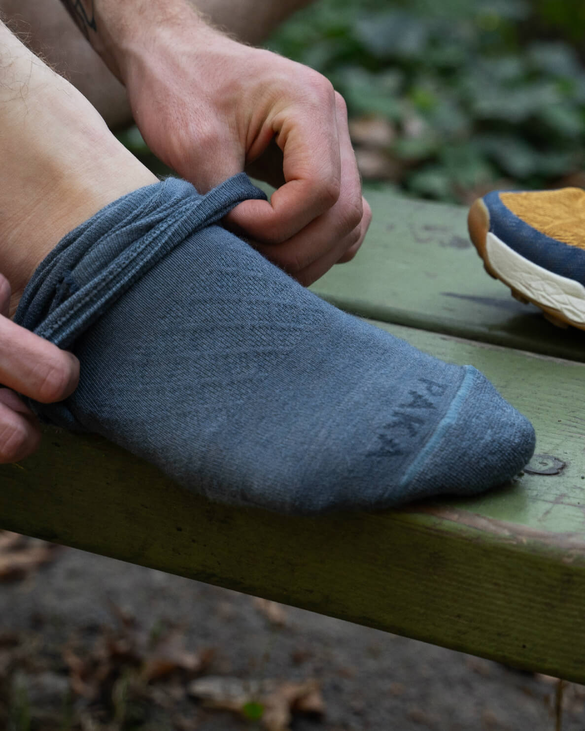 Indigo / Blue Alpaca Wool Sock Being Pulled Down on Man’s Right Foot on Bench – PAKA Apparel