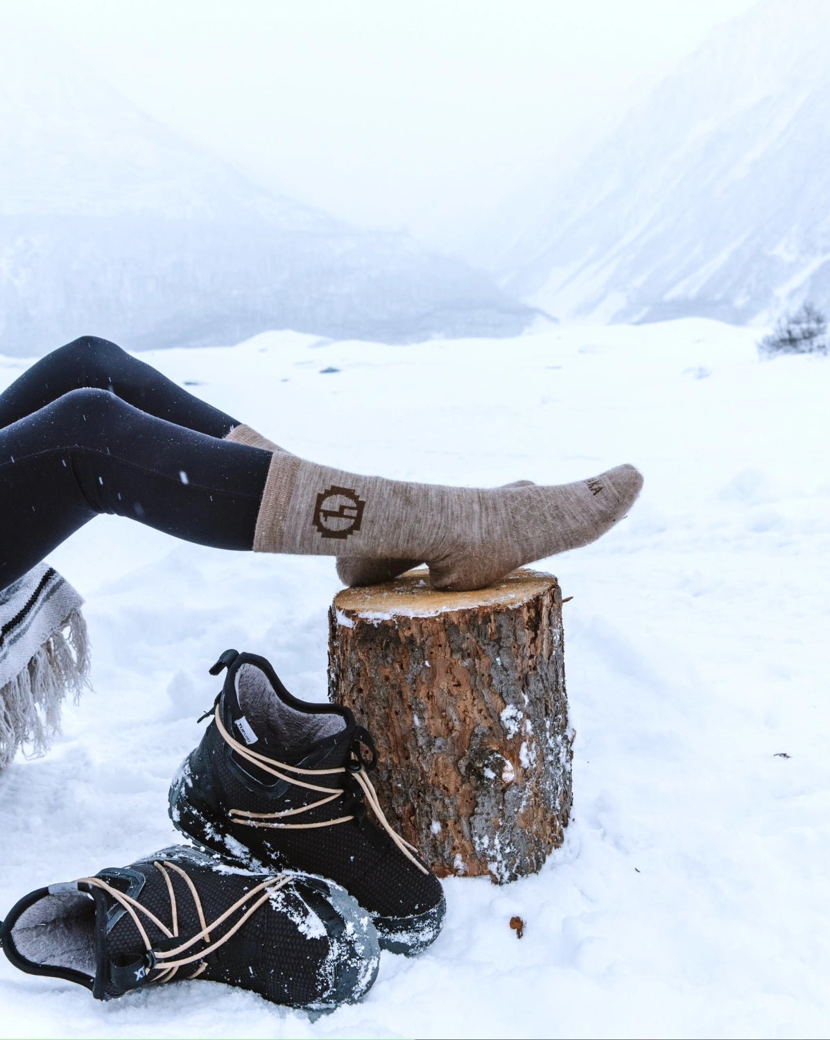 Timber / Tan Cozy Natural Fiber Alpaca Wool Crew Socks on Feet Resting on Stump in Snowy Mountains – PAKA Apparel