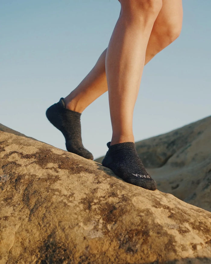 Woman walking down rock wearing dark grey alpaca ankle socks