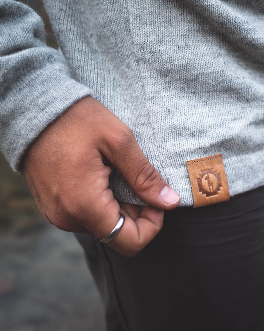 Close-Up of Man's Hand Holding Side of The Hoodie Light Grey Alpaca Wool Sweater Hoodie Near Branded Leather Tag – PAKA Apparel