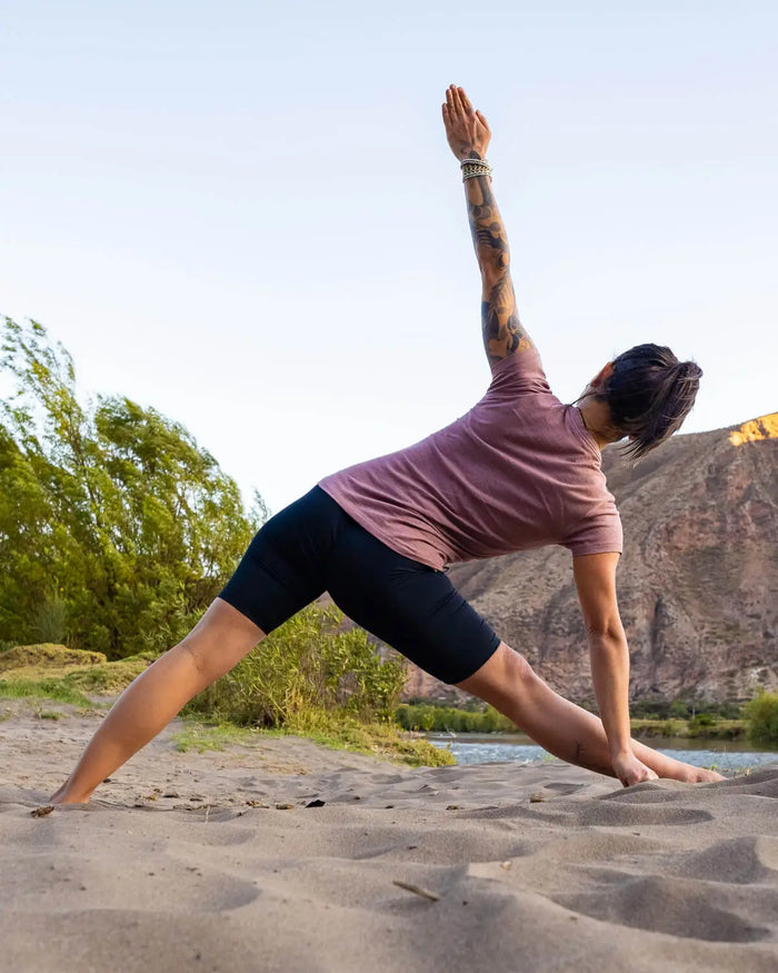 Woman Stretching to Yoga Pose in Sand Wearing Iris / Purple Lightweight Alpaca V-Neck T-Shirt – PAKA Apparel