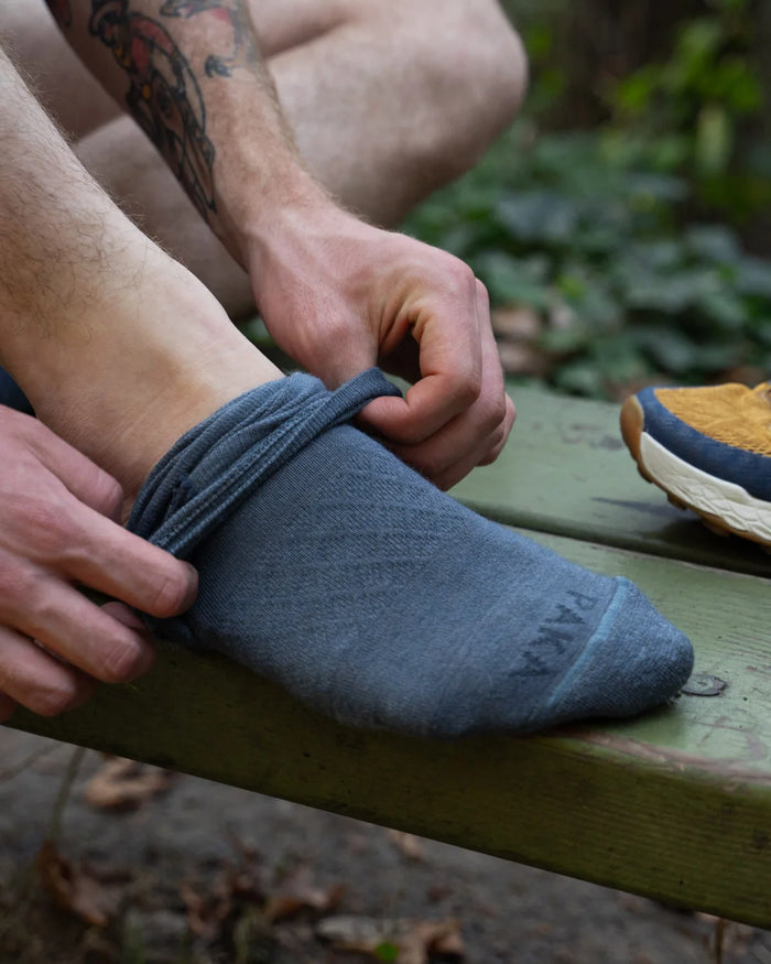 Man pulling on a blue alpaca wool sock 