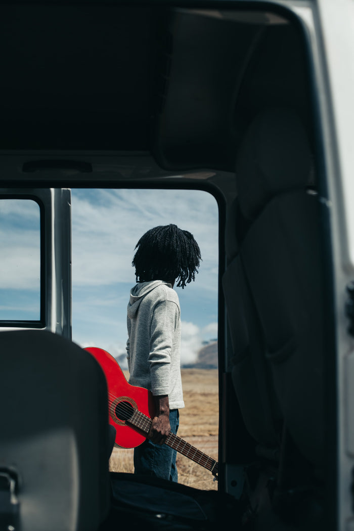 Male Model holding red guitar and looking at mountains in Paka Hoodie