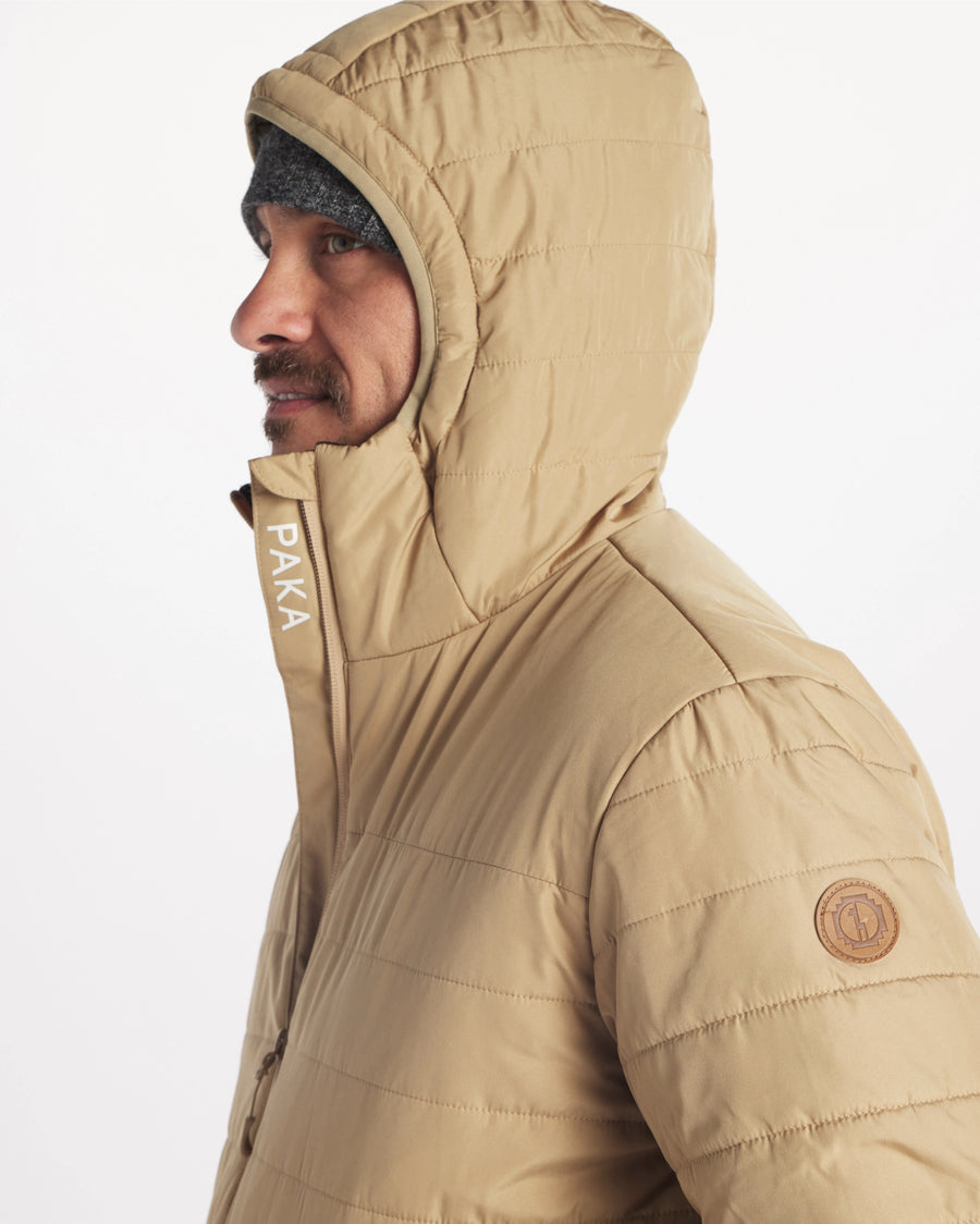 Side Profile of Model in Apu Tan Men’s Natural Fiber Midweight Puffer Jacket with PAKA Logo Tag on Arm – PAKA Apparel