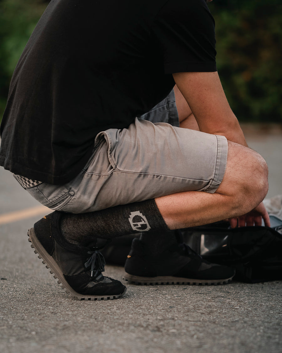 Male Model bending over in dark grey Paka socks on road